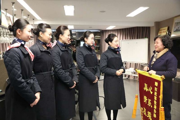 受助的刘阿姨和丈夫一起将致谢锦旗送到东航客舱部.jpg