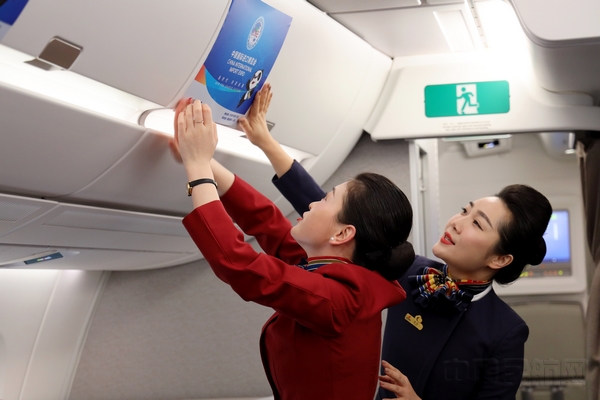 国航客舱乘务员在主题航班上粘贴进博会宣传海报（摄影：葛晗颖）.jpg