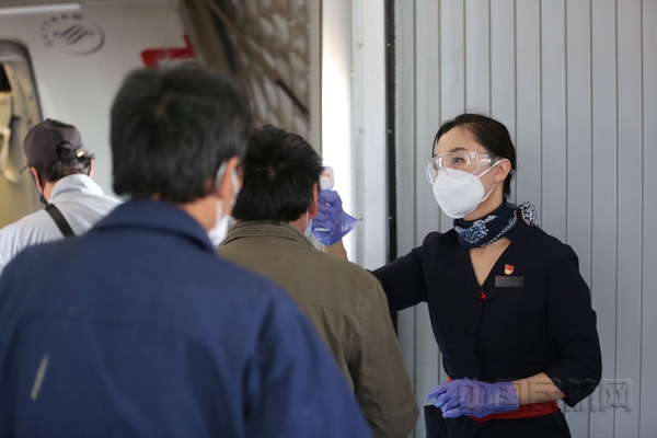 nEO_IMG_东航乘务员在做好自身防护的基础上,为登机旅客测温-东航供图